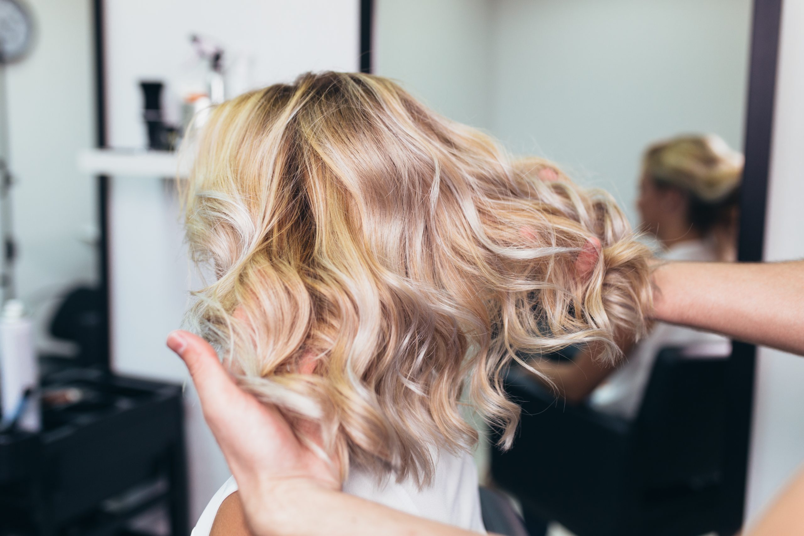 hairdresser running fingers through female blonde client's hair